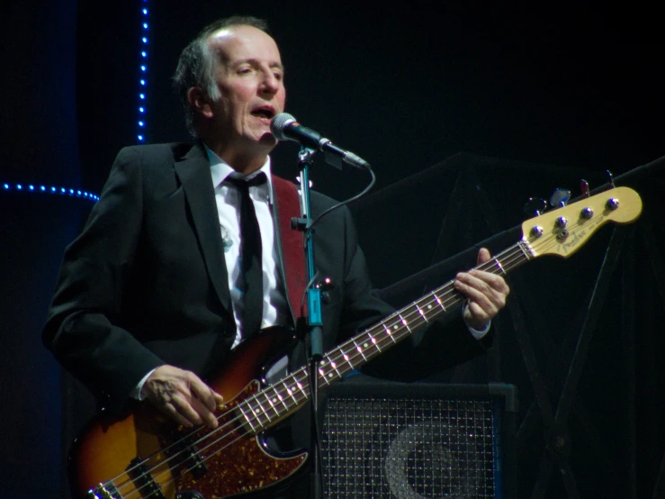 a man with an instrument standing in front of a microphone