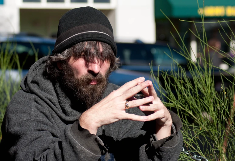 a bearded man in grey clothes and a black hat