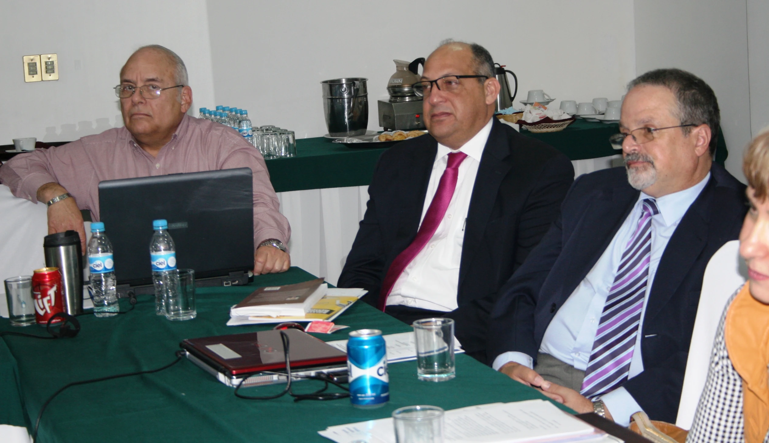 three men sitting next to each other at a green table