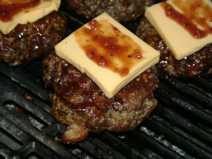 some cheeseburgers and hamburgers on a bbq grill