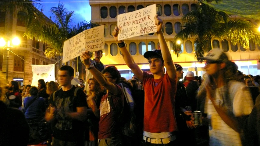 a man in a crowd holds up signs while holding a drink