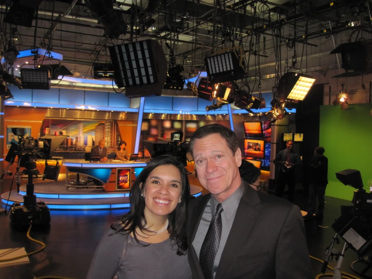 a man and woman posing for a picture in front of television studio sets