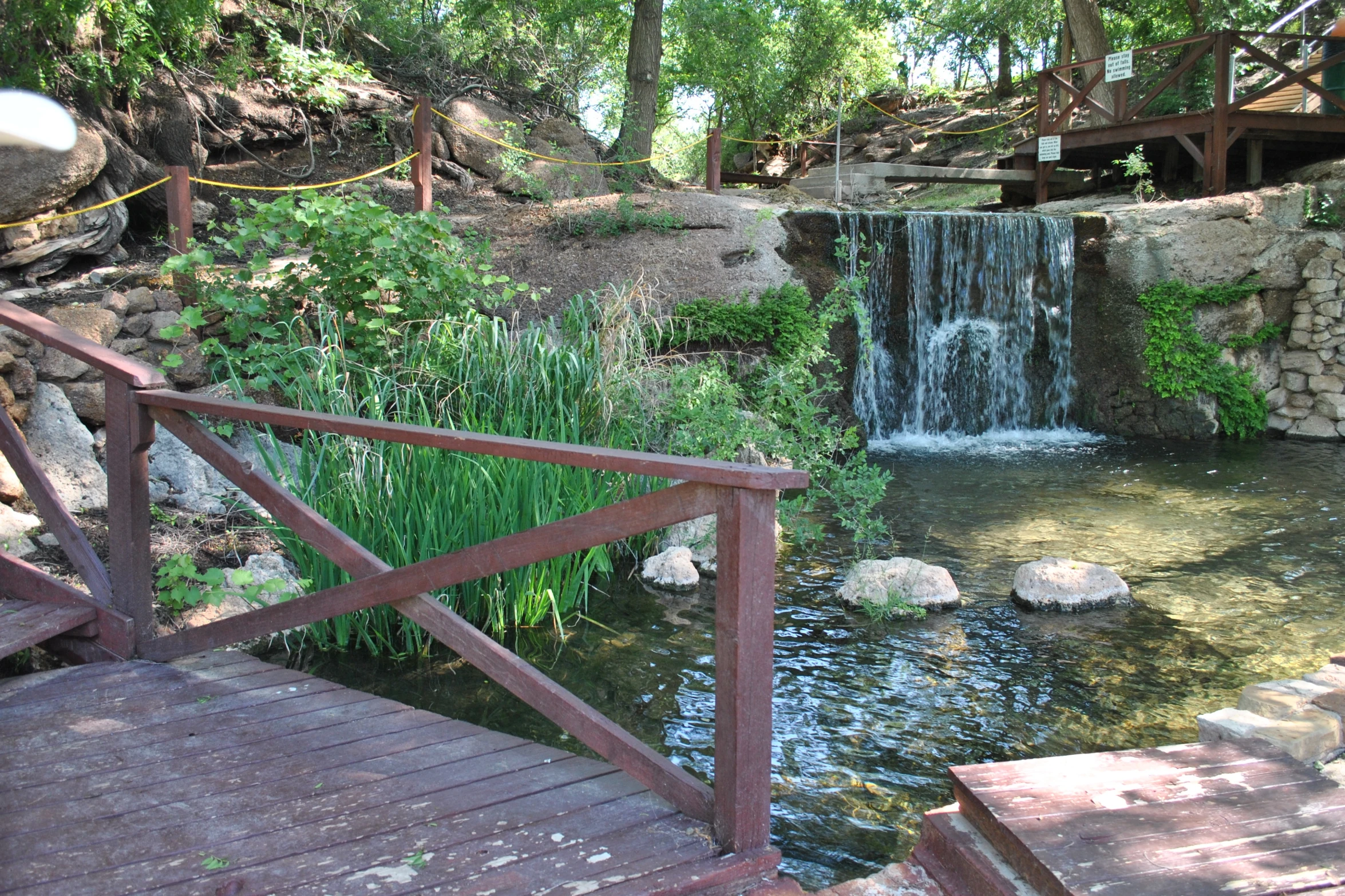 a small river flows near the rocks and a wooden bridge