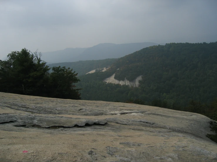 a view of a hillside in the distance from a rock