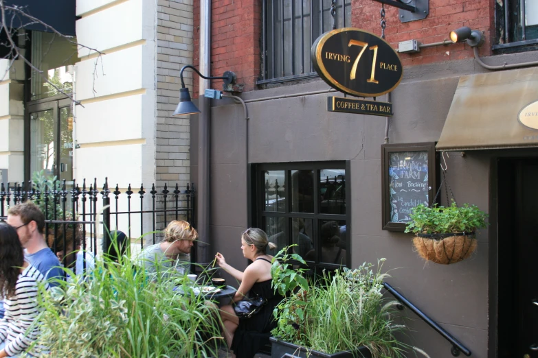 three people sitting on a bench next to a building