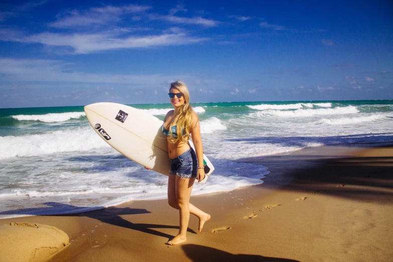 a young woman in a bikini holds her surfboard on the shore