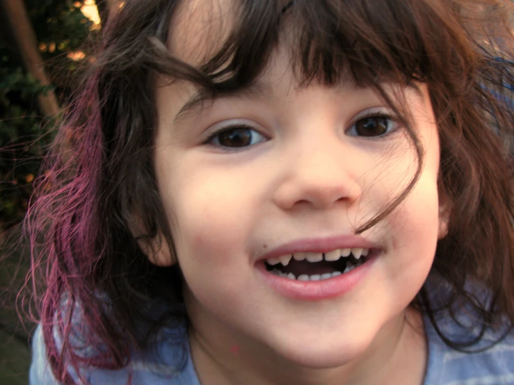 a little girl with purple hair has a missing tooth