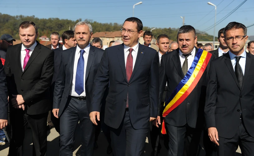 several people in suits and ties walking down the street