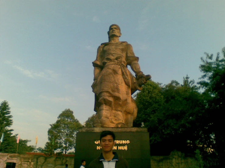 there is a man standing in front of a large statue