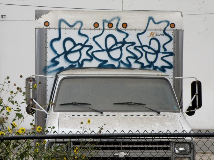 a white truck with blue graffiti and a bunch of flowers