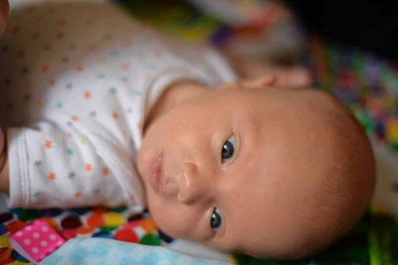 a baby looking directly at the camera while laying on a bed