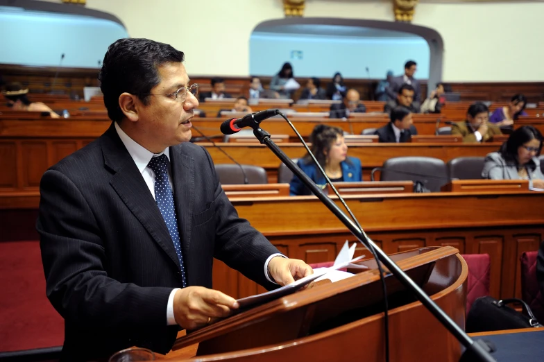 a man standing in front of a microphone while holding papers