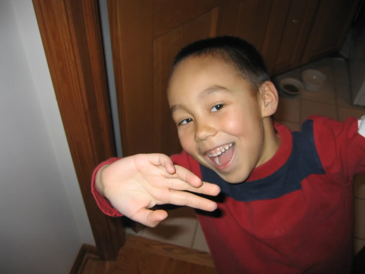 a boy smiling in the bathroom as he takes a po with his phone