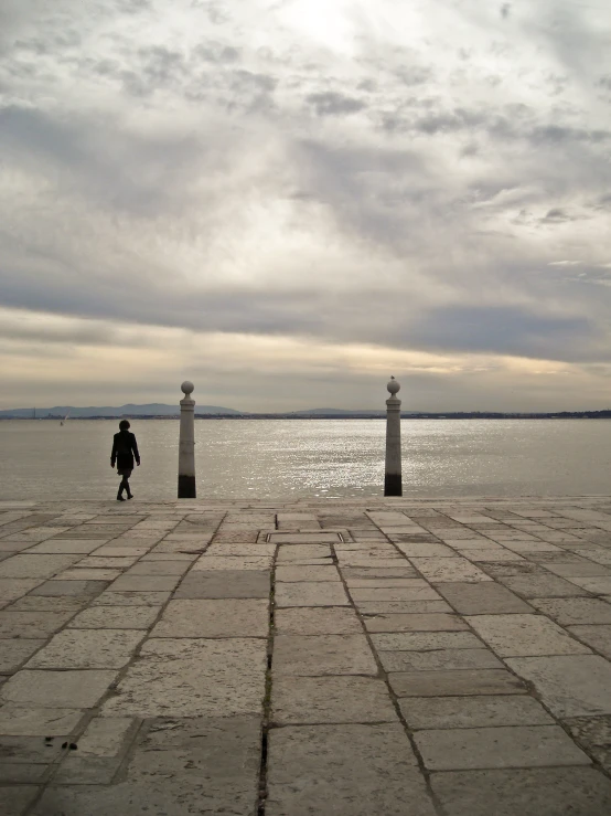 a person standing on top of a stone floor next to a body of water