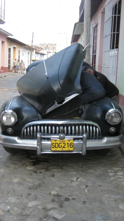 a man on top of a car with it's hood up