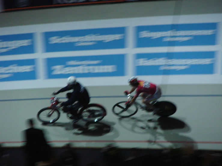 two men riding bicycles at a track event