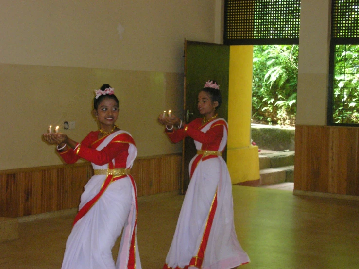 a couple of woman wearing fancy clothing standing next to each other