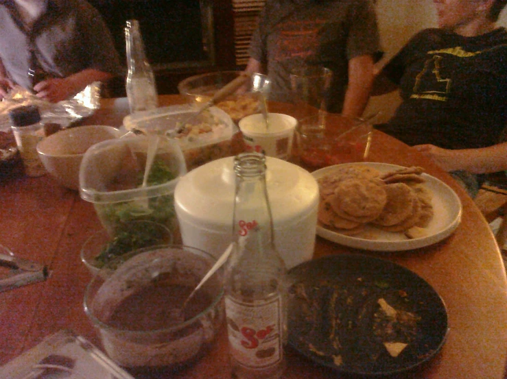 a table with a plate of food and drinks and many people in the background