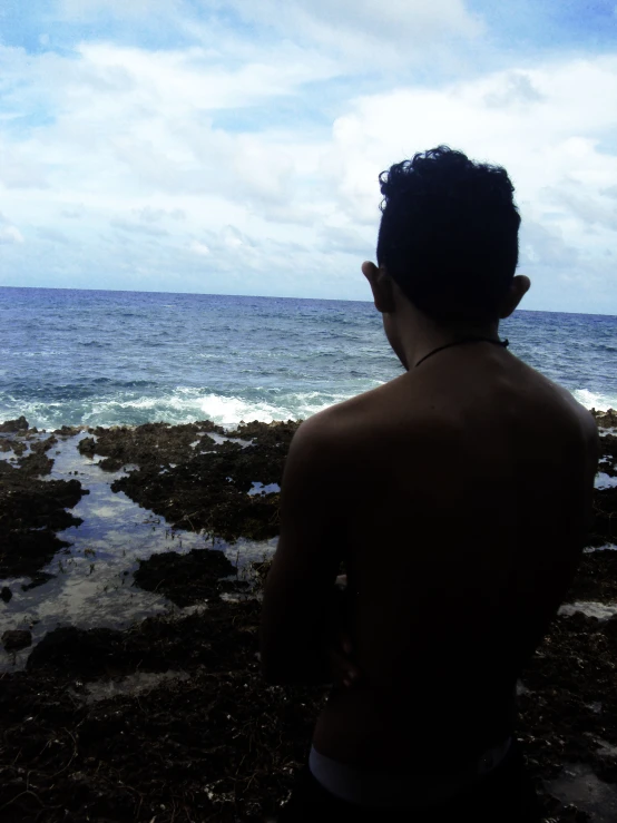 a young man is standing in front of the ocean