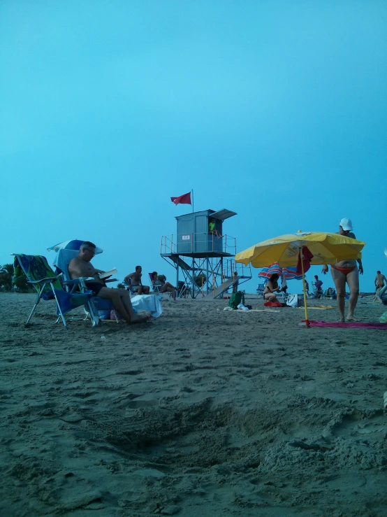 a crowd of people sitting and standing around a beach