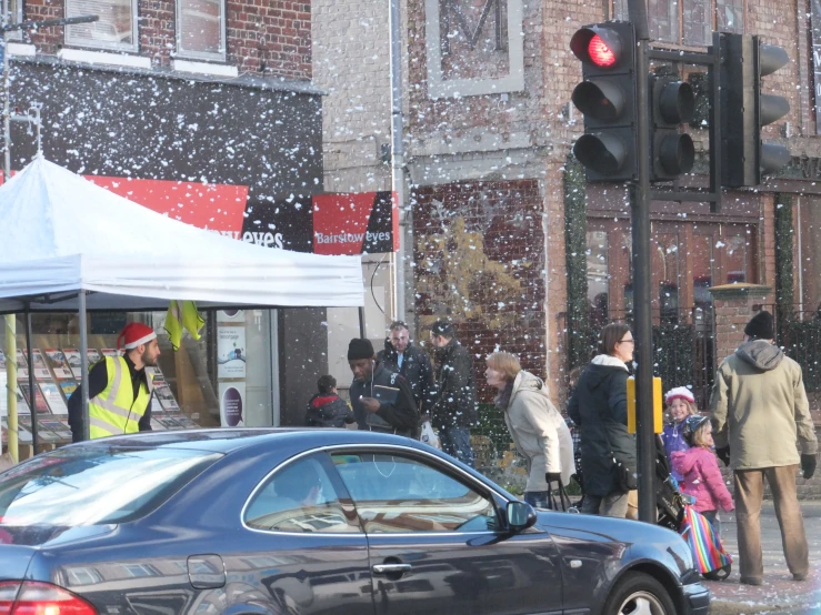 pedestrians stand under a traffic light in a snow storm