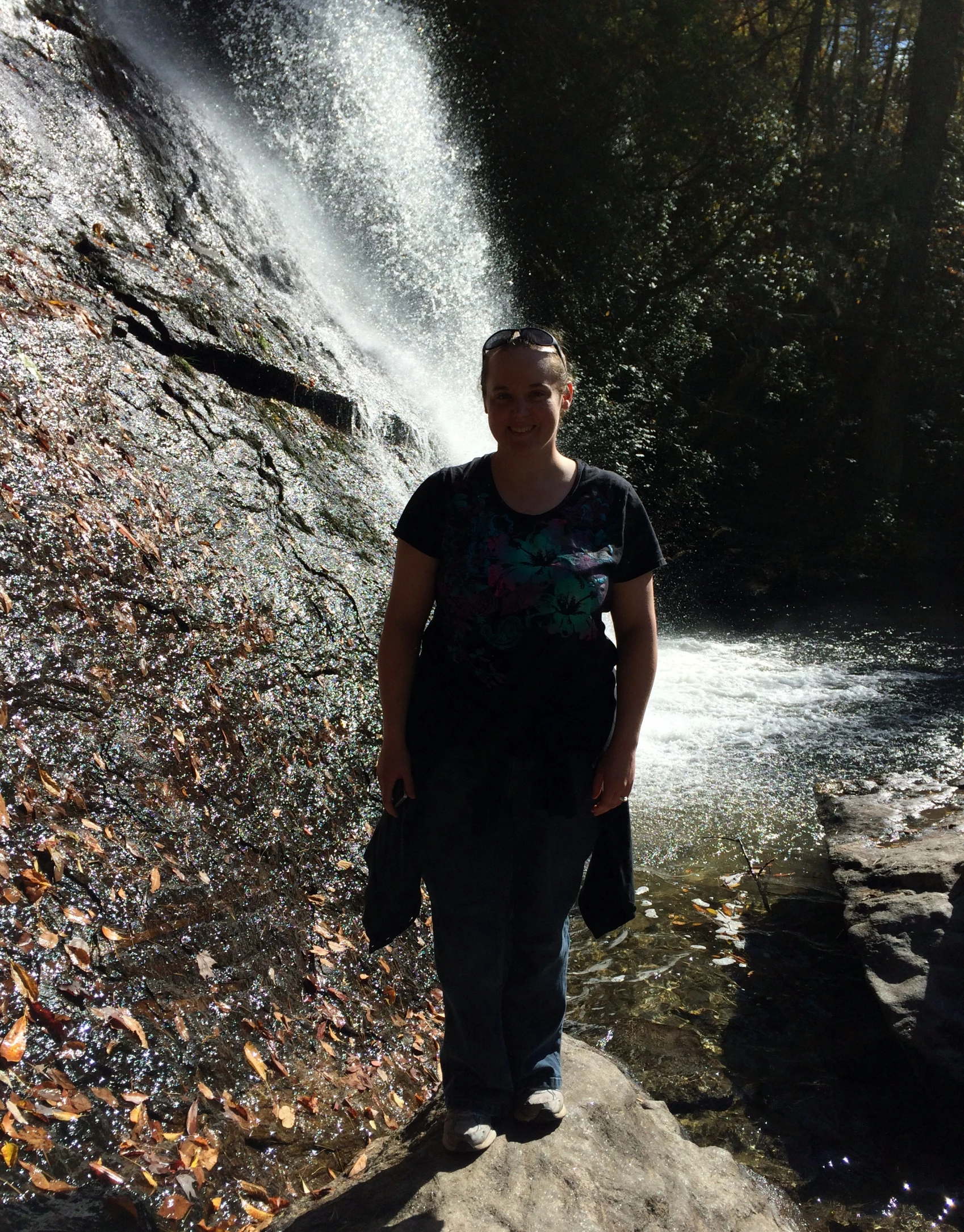 the woman is walking near a large waterfall