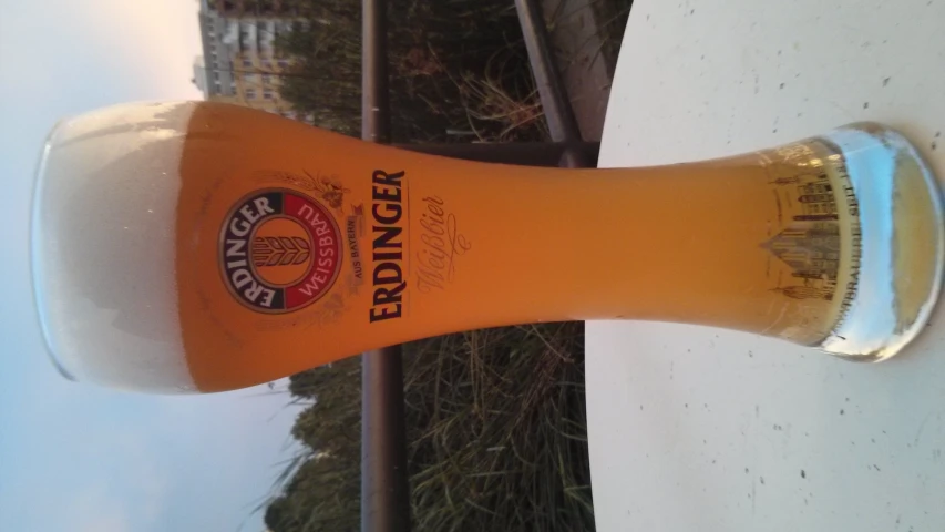 a glass full of beer sitting on top of a white table