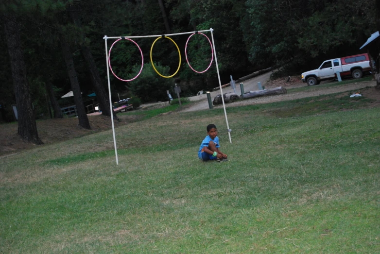 a child sitting on the grass with a toy in front of a large balloon arch