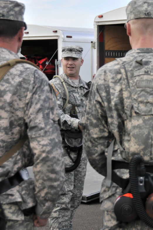 a soldier standing in front of a van talking to another person