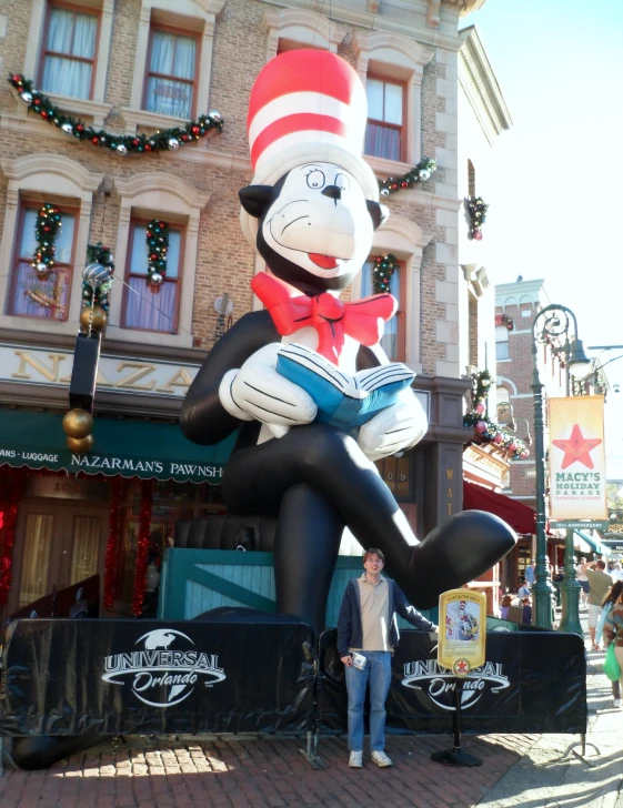 there is a large balloon statue made to look like a cat in the hat with a book on his lap