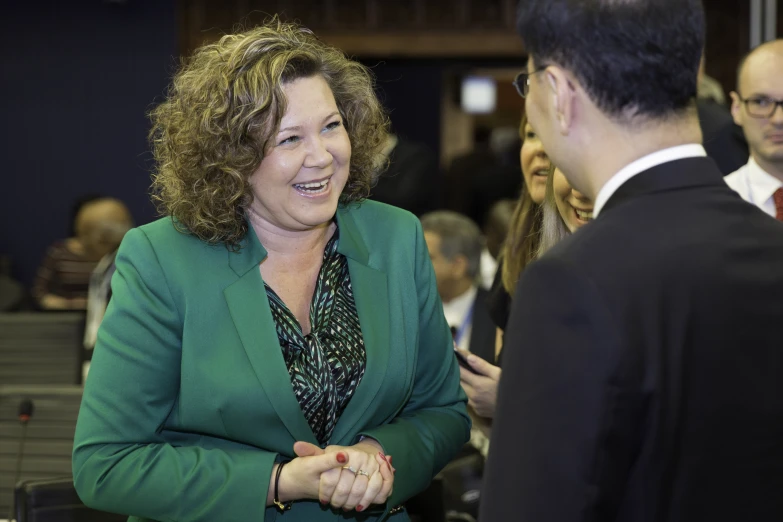 the woman smiles as she is greeting someone in a suit