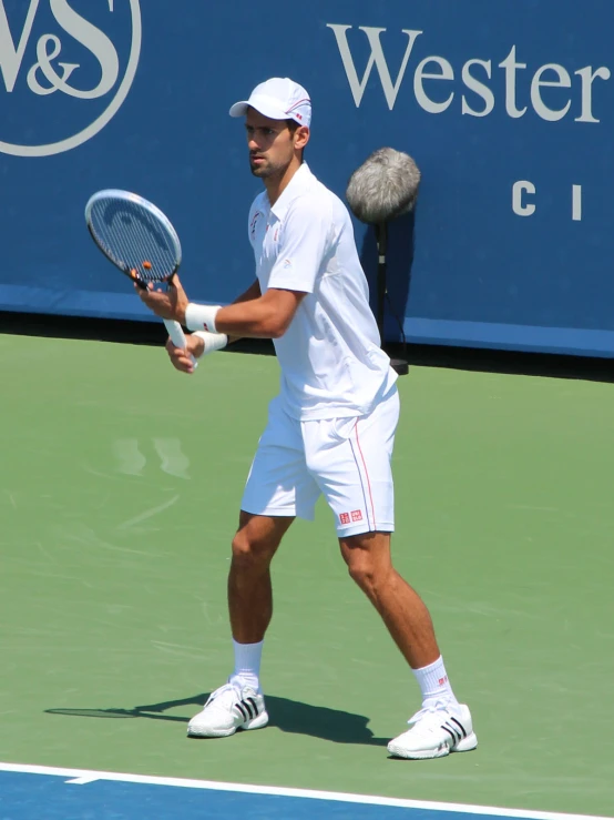 a man in white playing tennis is getting ready to serve the ball