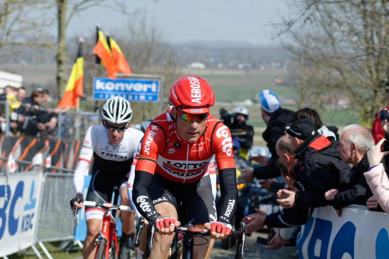 professional cycling on bicycle on course with large crowd watching