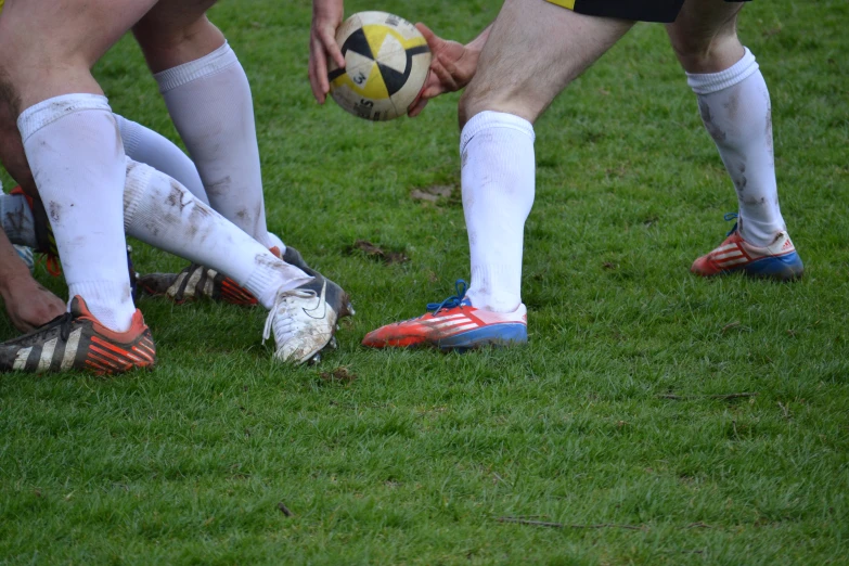 three people with socks are holding a soccer ball