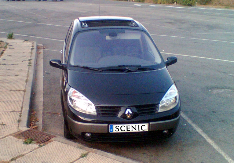 a small black car parked next to the side of a road