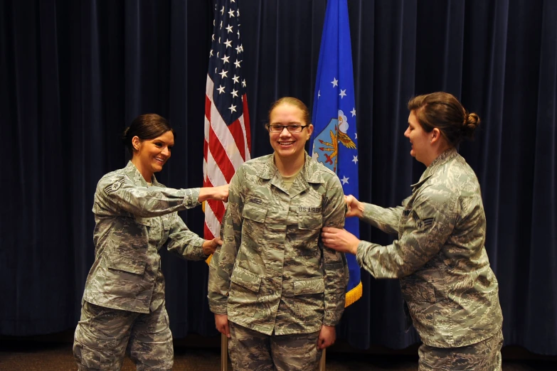 three women are in military uniform and have their hands on each other