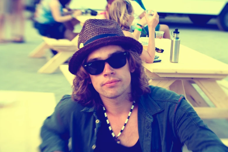 the man is wearing sunglasses, hat and holding a drink