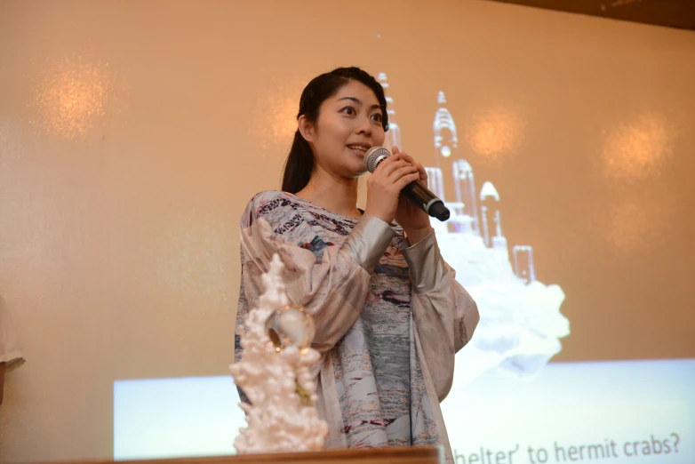 a girl holding a microphone standing in front of a projected screen