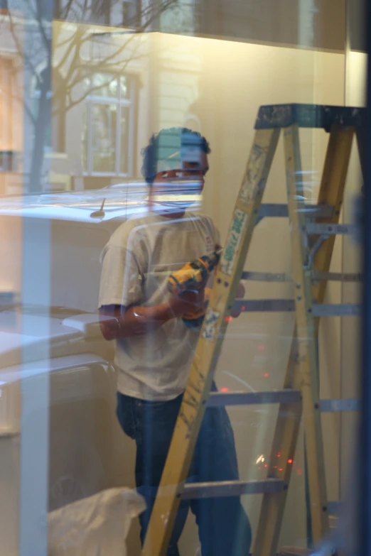 a man holding a pair of wrenches standing on a step ladder