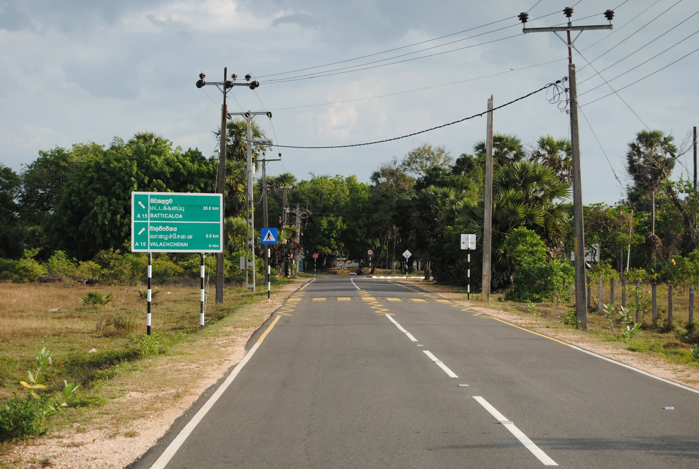 a sign for the road on a pole near some power lines