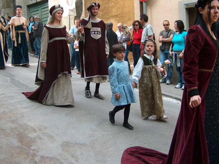 children walk together in long dresses on a street