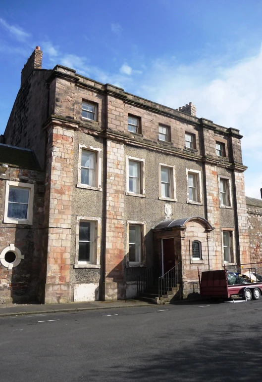 an old building with many windows sitting on the side of a road