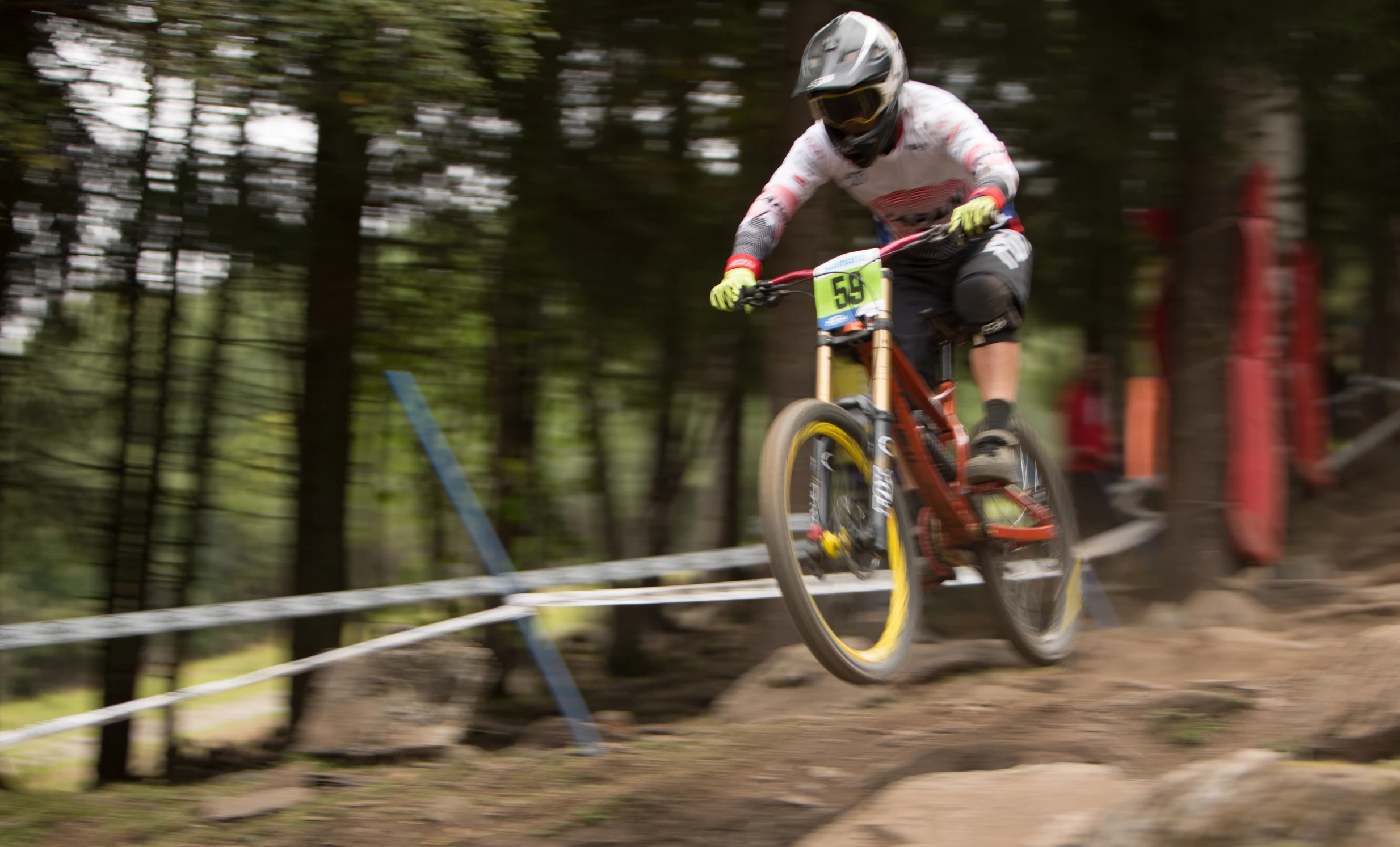 man jumping off the side of a bike in a forest