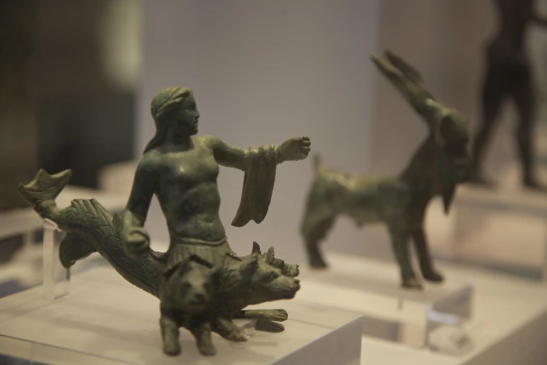 four ceramic figurines sit on display with white stands