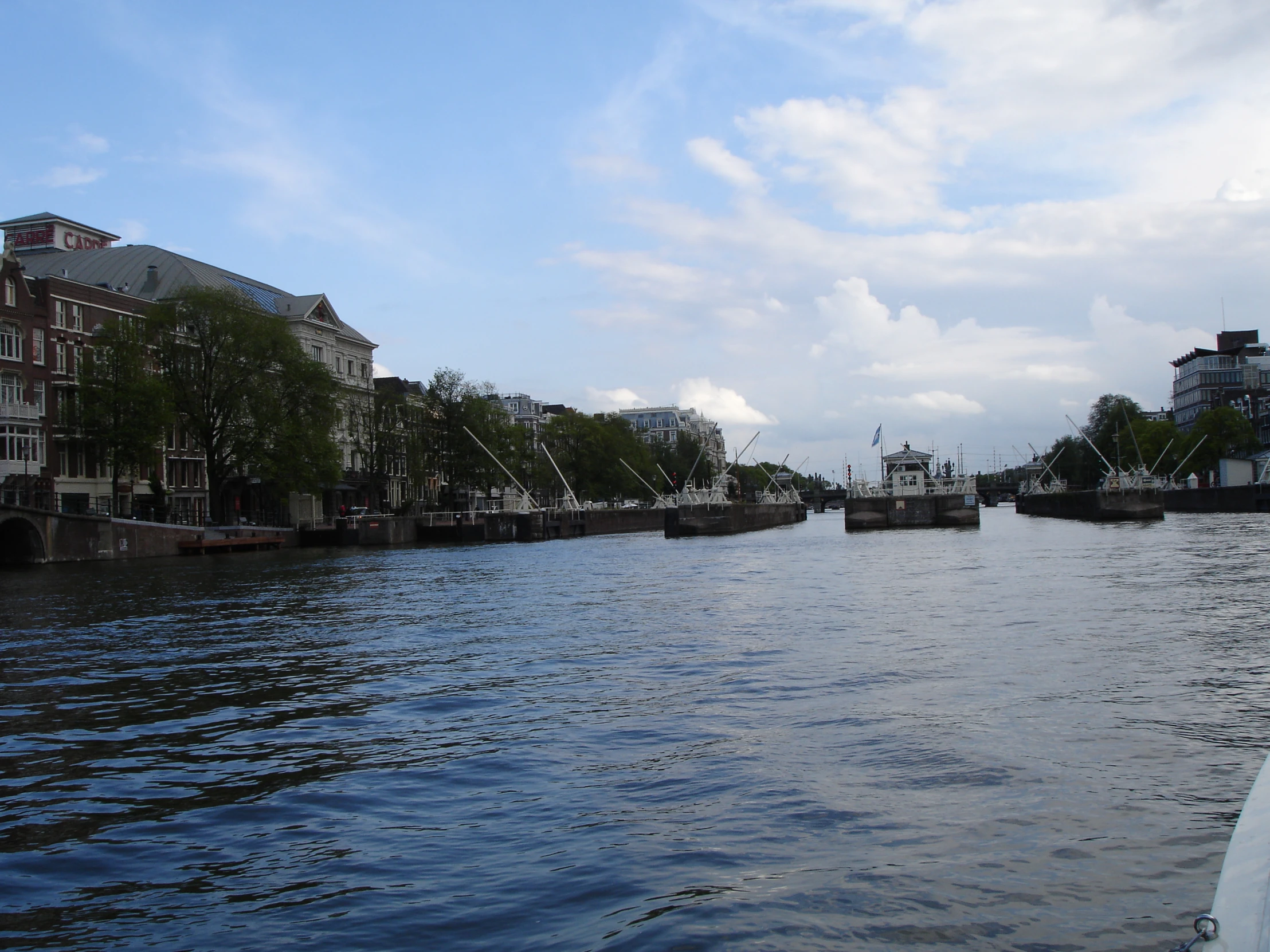 the river runs alongside some buildings and boats