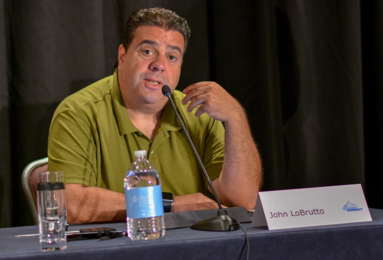 a man sits at a table with a microphone