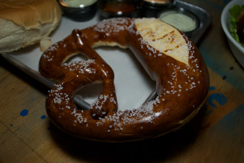 a couple of pretzels on a tray by some food