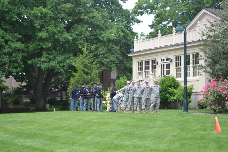 the men are standing in front of the house and a bunch of trees