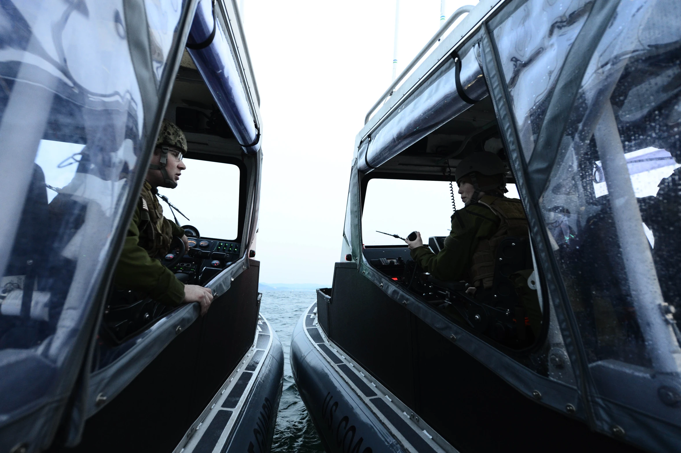 two people sitting in boats with their helmets on