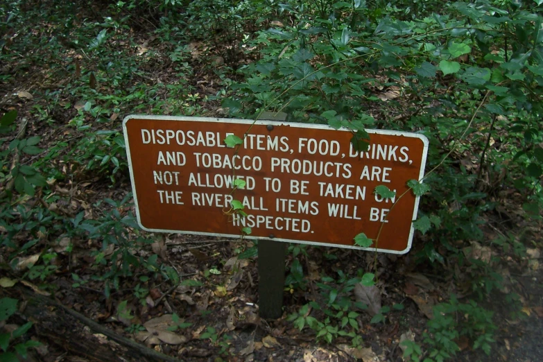 a sign is posted on a trail in a forest